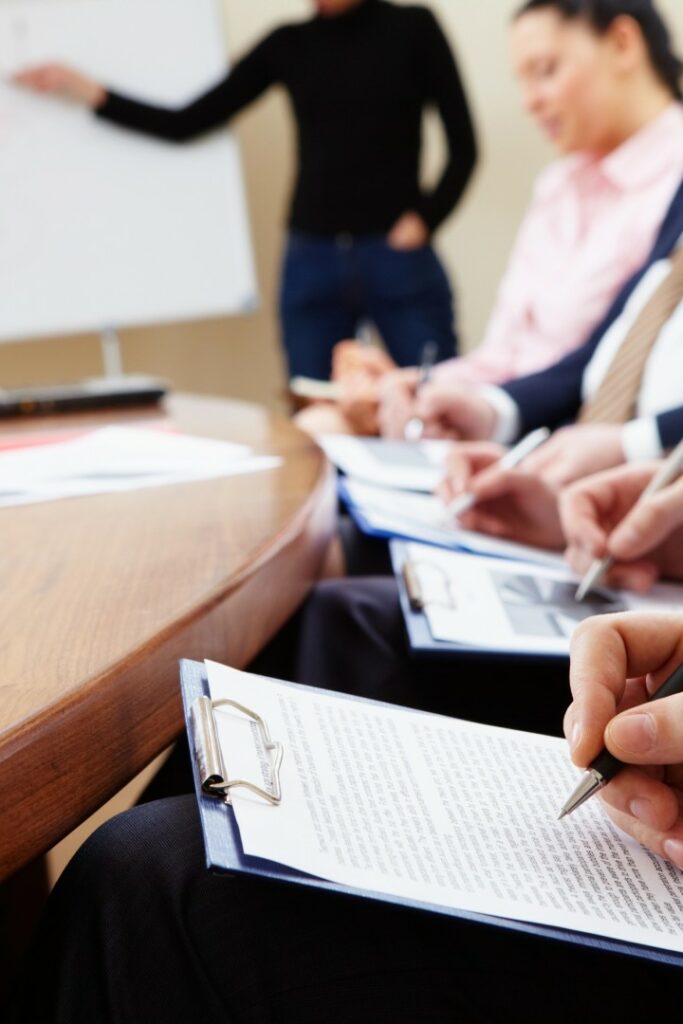Corso di formazione con persone che prendono appunti e relatore alla lavagna